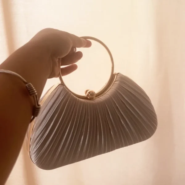 Customer holding white pleated women handbag with gold ring handle