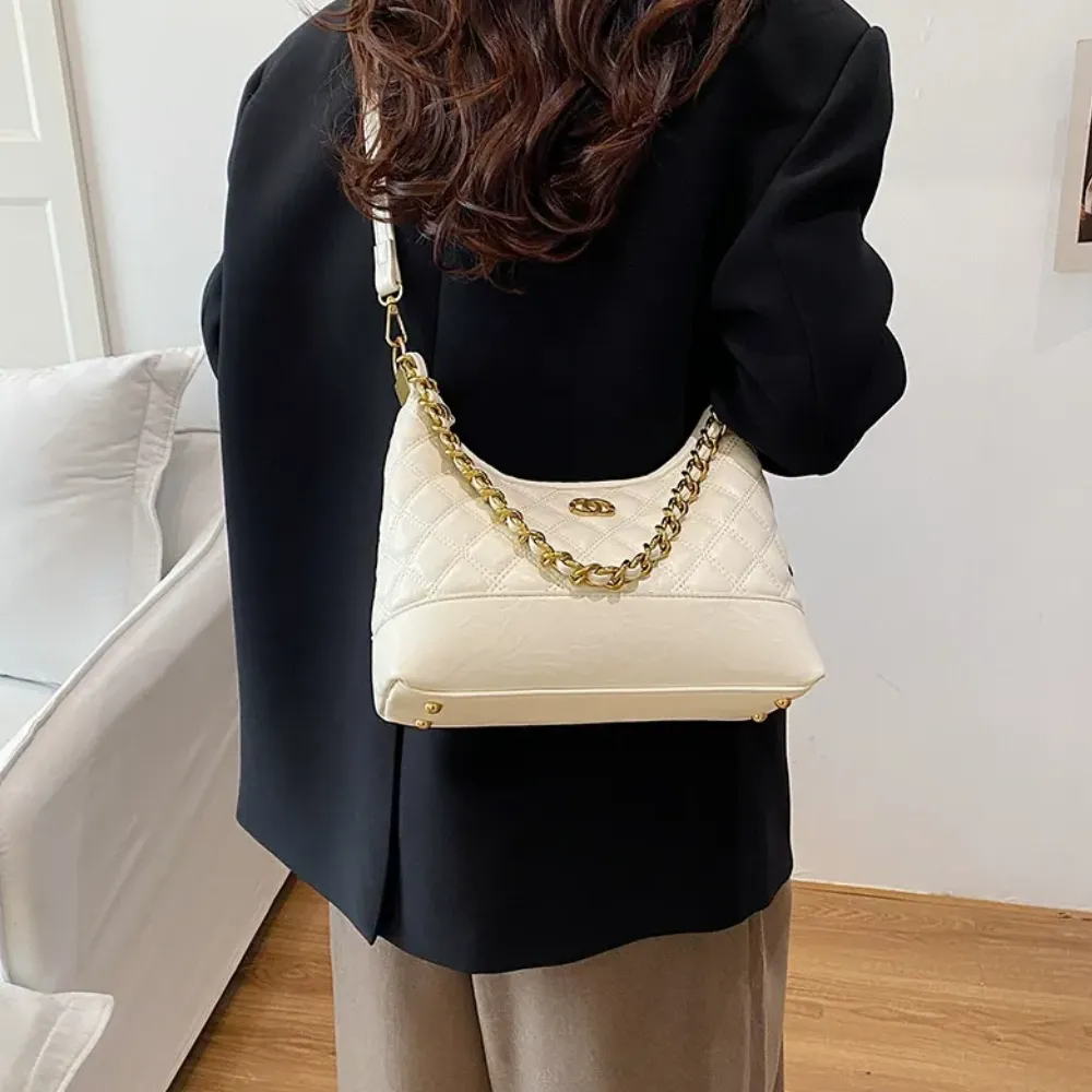 Woman carrying a white leather shoulder bag with chain strap