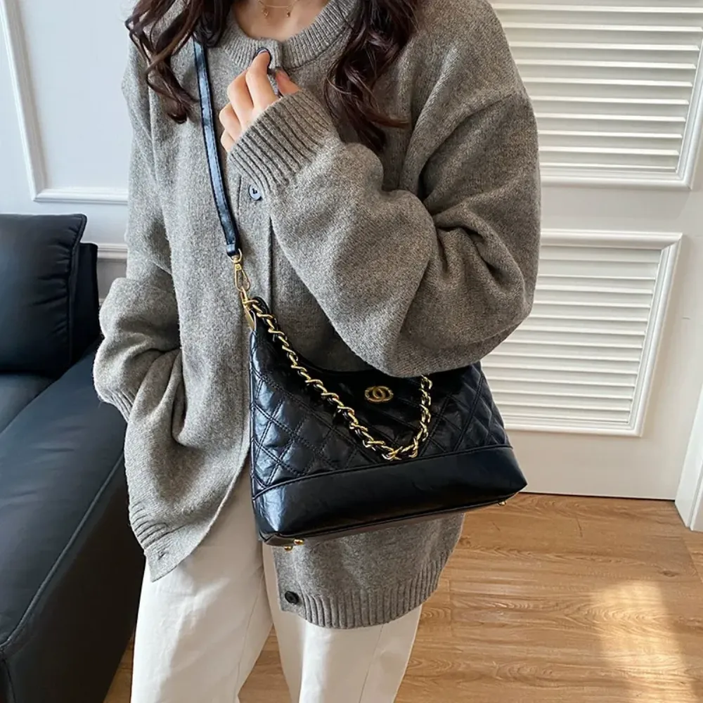 Woman wearing a black shoulder bag with gold chain strap